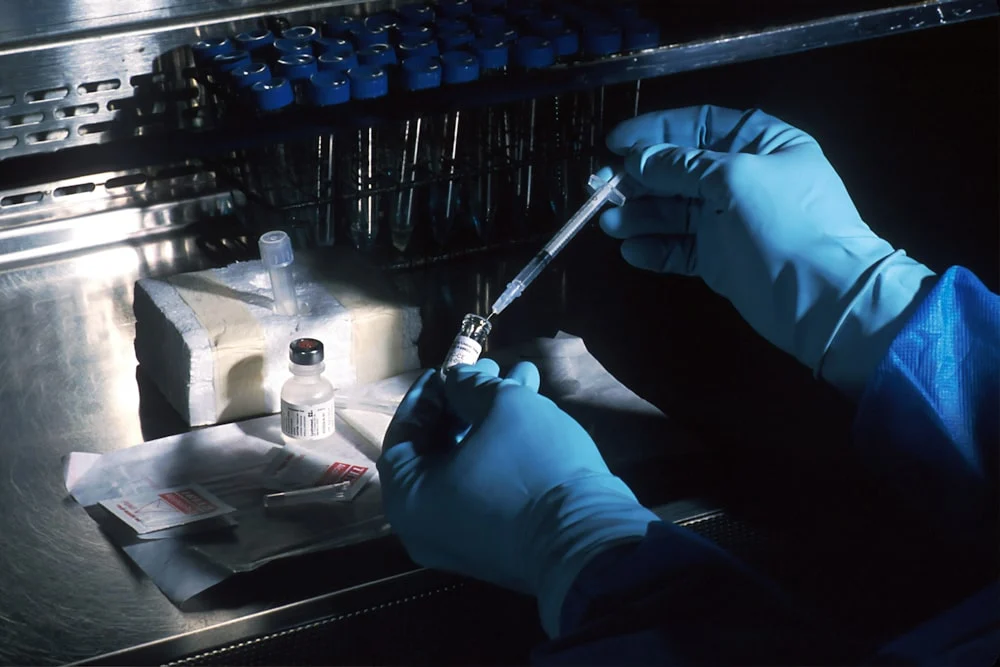 clinical trial seo gloved hands drawing vaccine from vial with syringe