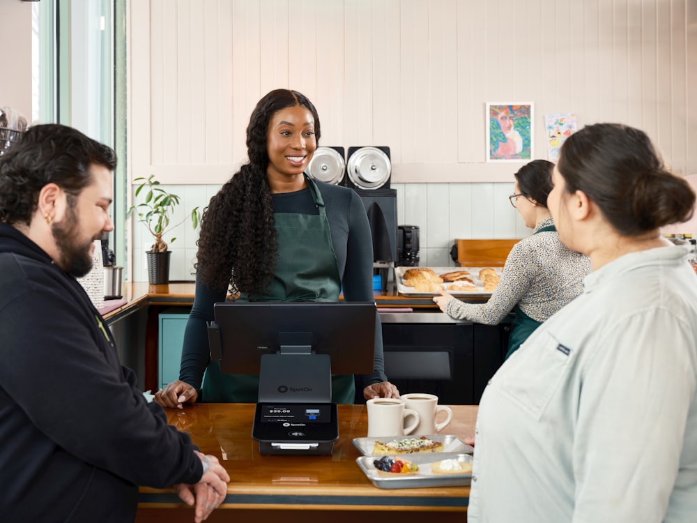 TouchBistro API and Custom Integrations for Restaurants 27 A smiling woman serves customers at a cafe counter.