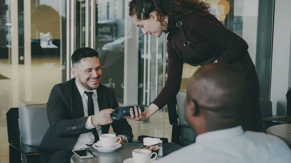 Fooda employee retention marketing Man pays with credit card at cafe table